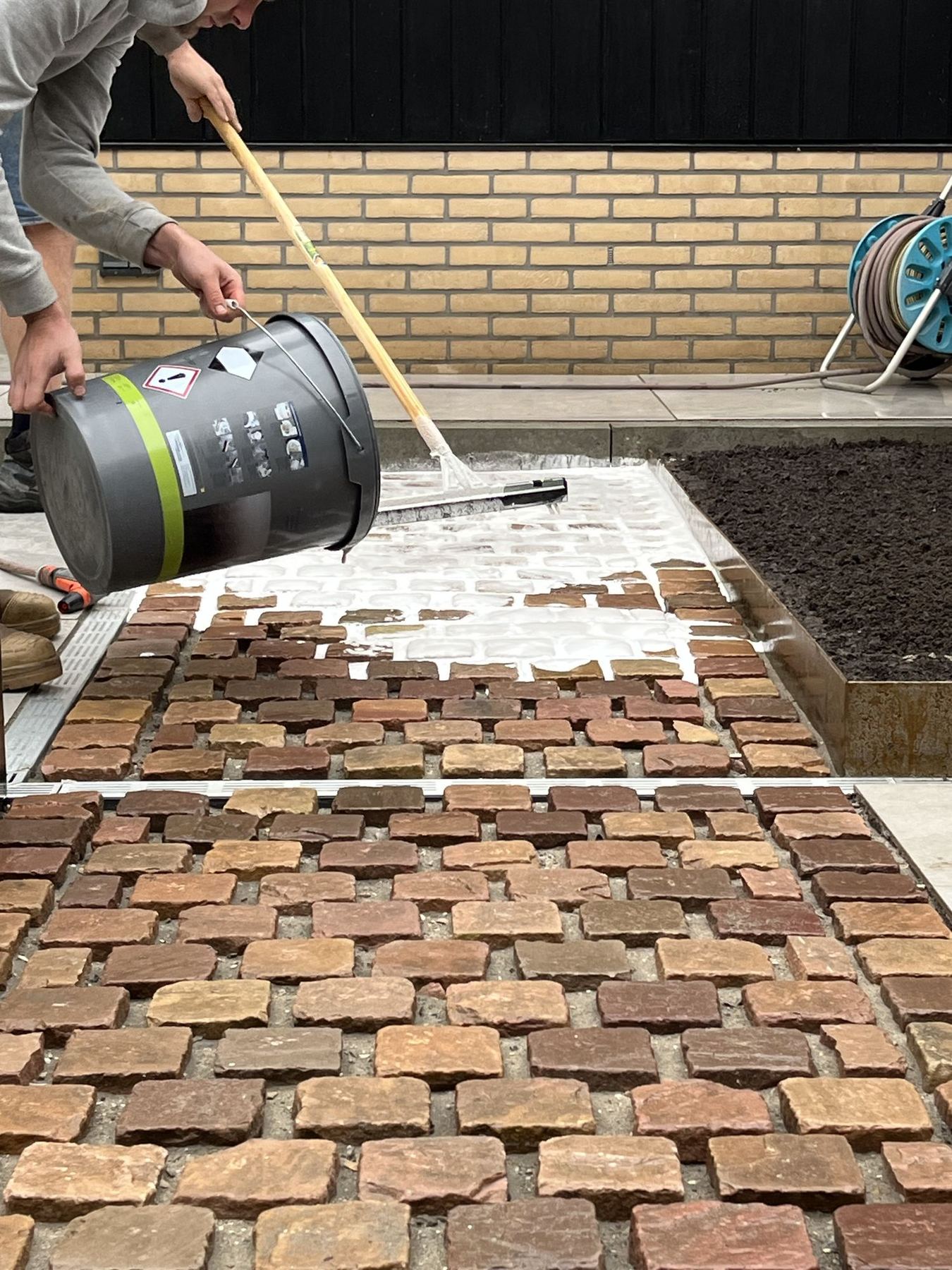 Kasseien worden ingeveegd tijdens de tuinaanleg