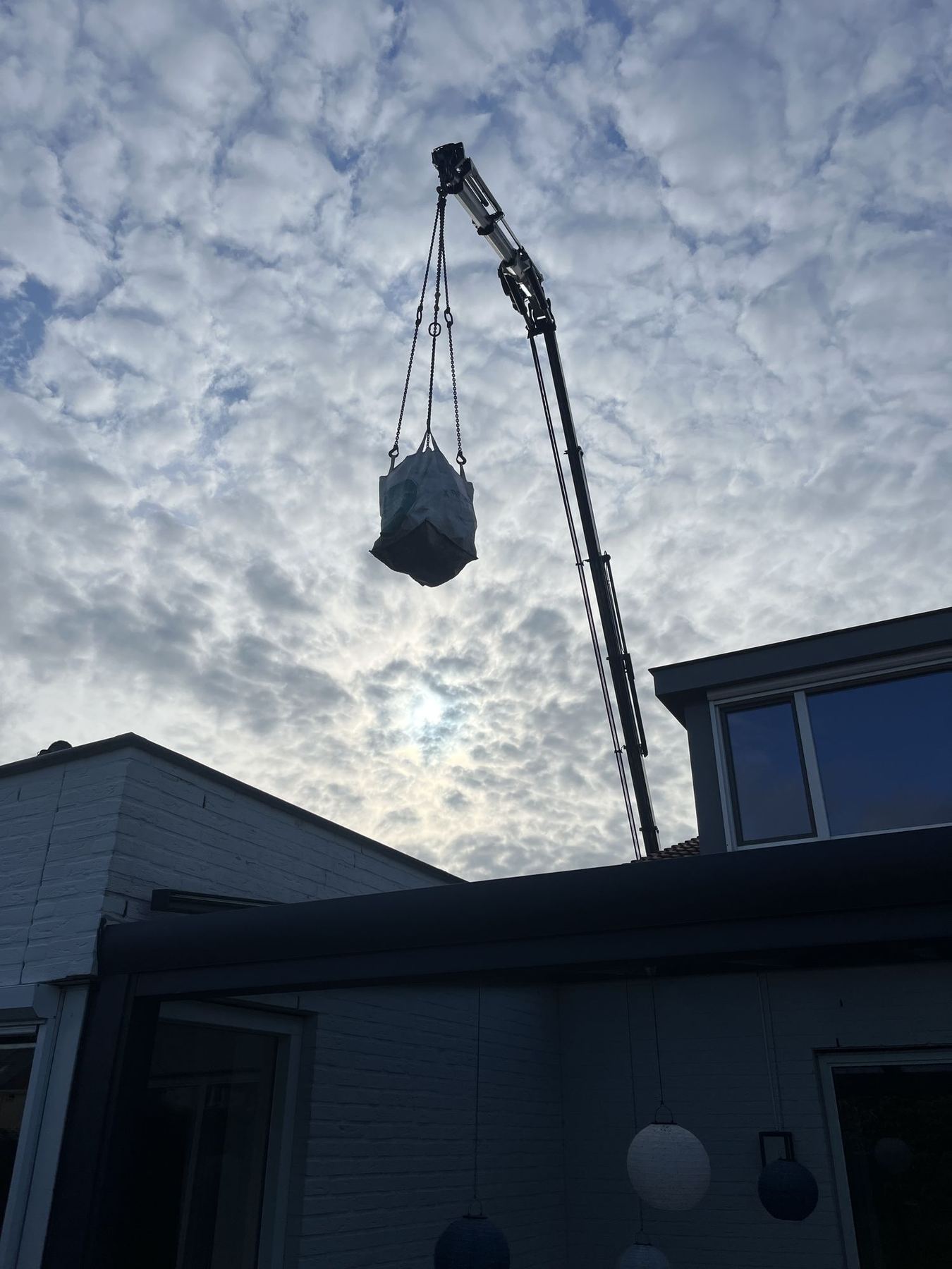 Materiaal wordt met een kraan over de woning gehesen